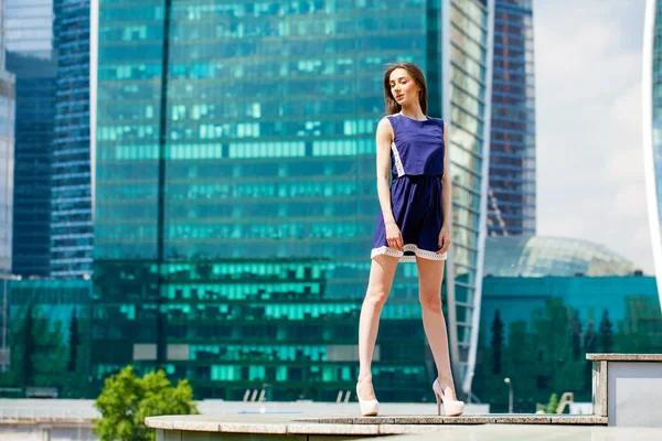 Giovane donna in abito blu si estende vicino a grattacieli — Foto Stock