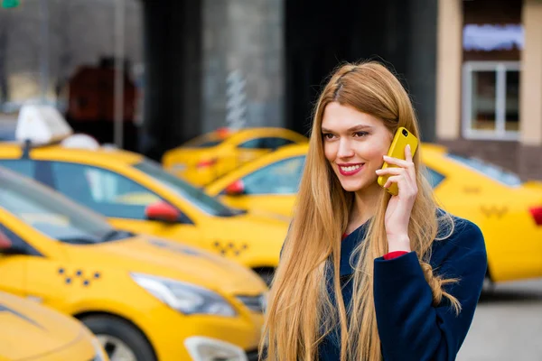 Een jong meisje roept een taxi via de telefoon. — Stockfoto