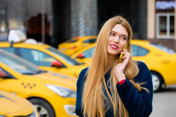 Una joven llama a un taxi por teléfono . — Foto de Stock