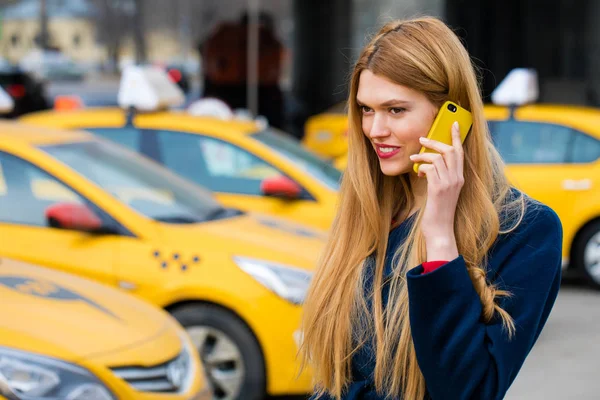 En ung flicka ringer en taxi via telefon. — Stockfoto