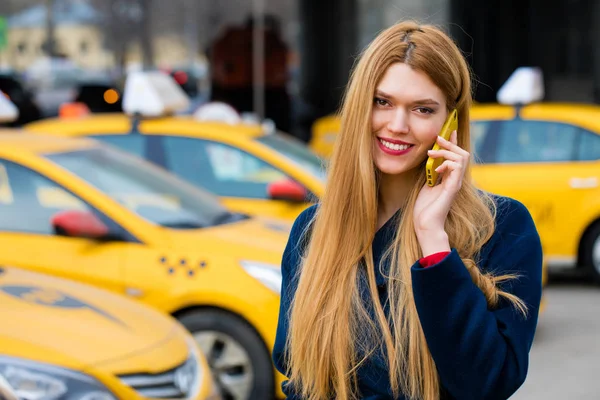 Una joven llama a un taxi por teléfono . — Foto de Stock