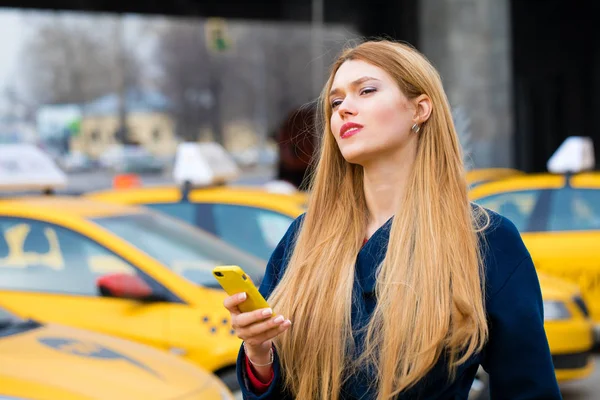 Een jong meisje roept een taxi via de telefoon. — Stockfoto