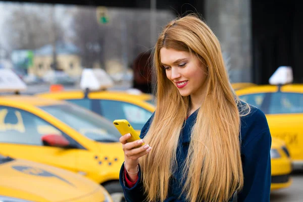 En ung flicka ringer en taxi via telefon. — Stockfoto