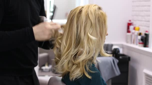 Cabelo de estilo no salão de beleza. Calmo bela mulher loira em um cabeleireiro — Vídeo de Stock