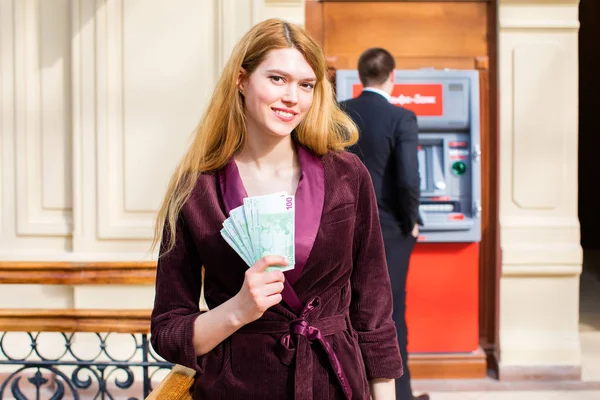 Mujer rubia joven está sosteniendo un dinero en efectivo —  Fotos de Stock