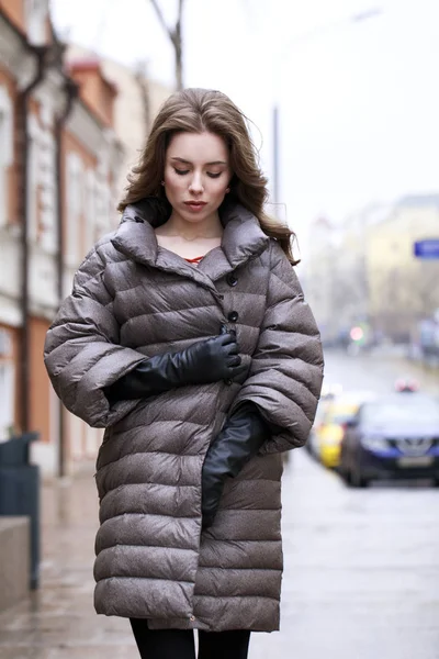 Porträtt av en ung snygg brunett flicka i en grå dunjacka — Stockfoto