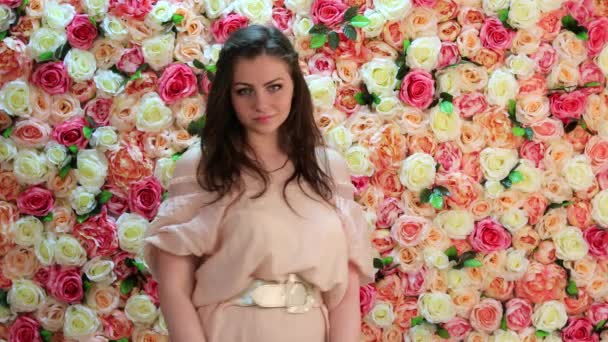 Повітряний поцілунок. Портрет молодої сексуальної моделі в рожевій сукні, фон яскравої квіткової стіни — стокове відео