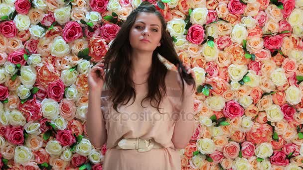 Portret van een jonge vrouw in roze jurk, achtergrond van de heldere floral wall — Stockvideo