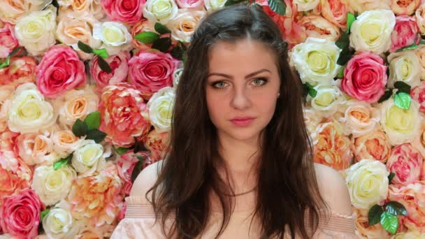 Teken de stilte. Portret van jonge mooie brunette, close-up op een achtergrond van lichte floral muur — Stockvideo