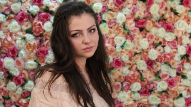 Retrato de joven hermosa morena, de cerca sobre un fondo de brillante pared floral — Vídeos de Stock