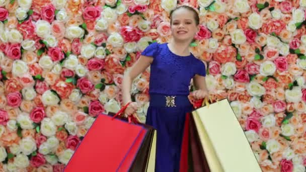 Childrens shopping. Porträtt av glad liten flicka i klänning, bakgrund av ljusa blommiga väggen — Stockvideo