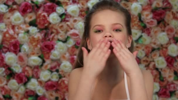 Levegő Bene. Kislány fehér ruhában pózol a háttér egy virág fal a stúdióban — Stock videók