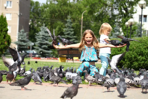 Happy little girl feeding doves in the city street — Stock Photo, Image