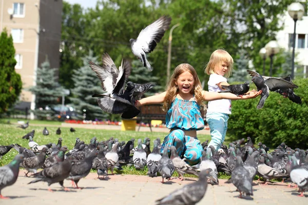 Счастливая маленькая девочка кормит голубей на городской улице — стоковое фото