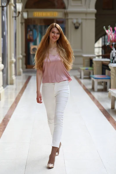 Jeune belle femme blonde en pantalon blanc et chemisier rose — Photo