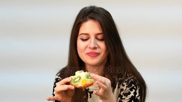 Tartlets. Mulher morena bonita comendo um bolo de creme — Vídeo de Stock