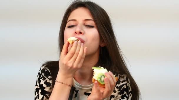 Tartaletas. Feliz hermosa mujer morena comiendo un pastel de crema — Vídeos de Stock