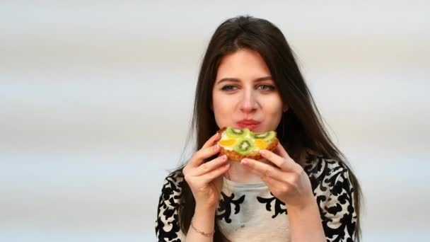 Tartlets. Jovem bela mulher morena comendo um bolo de creme — Vídeo de Stock