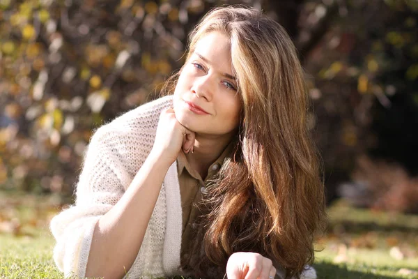 Mulher loira posando deitada no gramado no parque de outono — Fotografia de Stock