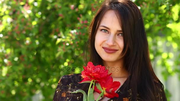 Tulipanes florecientes. Mujer hermosa feliz con tulipanes rojos, primavera al aire libre — Vídeos de Stock