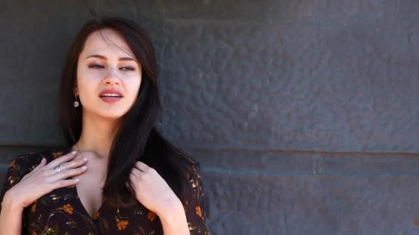 Beauty Model. Young beautiful woman in a summer dress posing against a background of an iron wall — Stock Video