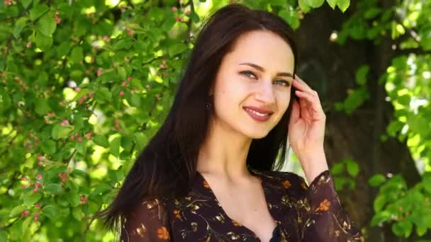 Feliz Morena. Joven hermosa mujer en un vestido de verano posando contra el parque de primavera al aire libre — Vídeo de stock