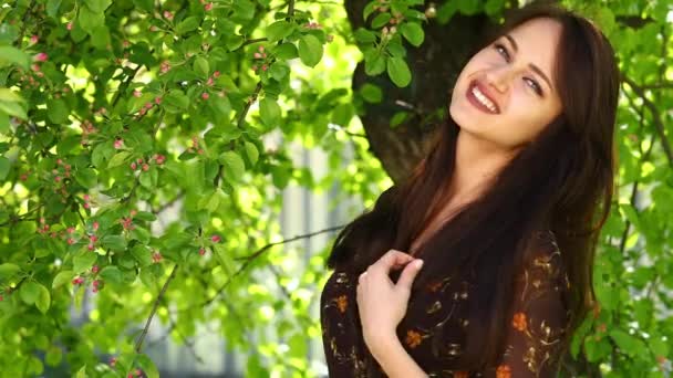 Feliz Morena. Joven hermosa mujer en un vestido de verano posando contra el parque de primavera al aire libre — Vídeos de Stock