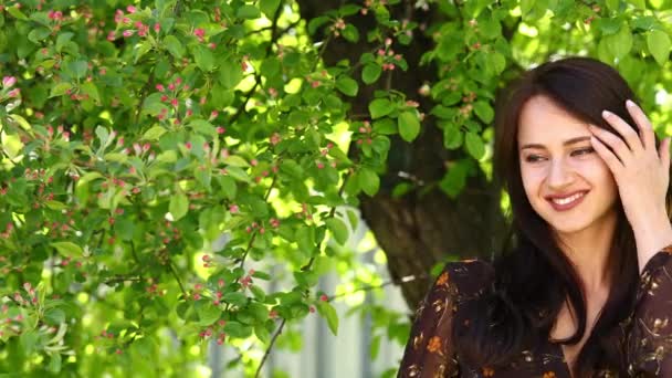 Feliz Morena. Joven hermosa mujer en un vestido de verano posando contra el parque de primavera al aire libre — Vídeos de Stock