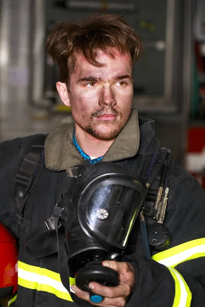 Retrato de um jovem bombeiro no fundo de um caminhão de bombeiros — Fotografia de Stock