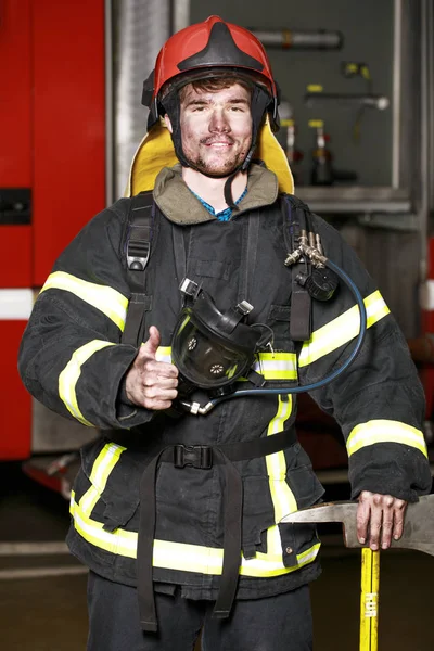 Portret młodego strażak na tle strażacki — Zdjęcie stockowe