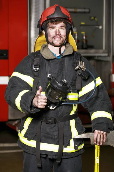 Retrato de um jovem bombeiro no fundo de um caminhão de bombeiros — Fotografia de Stock