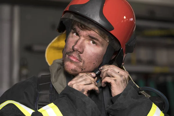 Retrato de um jovem bombeiro no fundo de um caminhão de bombeiros — Fotografia de Stock