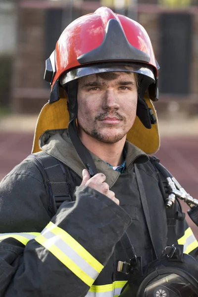 Retrato de um jovem bombeiro no fundo de um caminhão de bombeiros — Fotografia de Stock