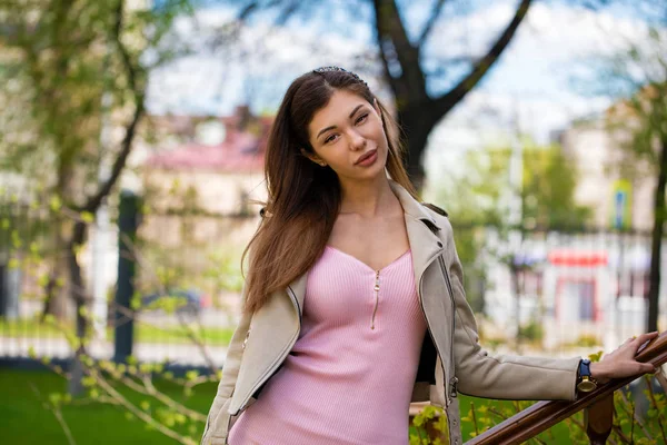 Hermosa joven morena mujer en vestido rosa y chaqueta gris — Foto de Stock