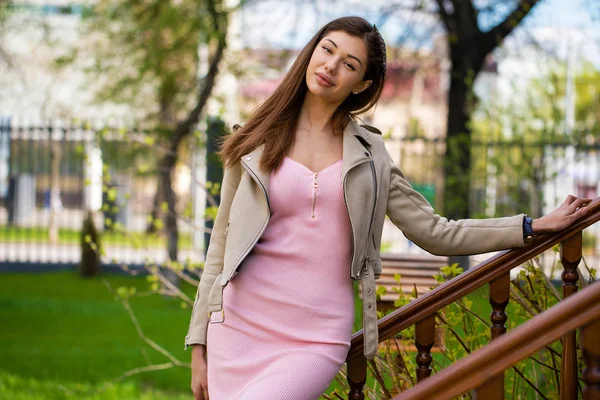 Krásná mladá brunetka žena v růžových šatech a šedá bunda — Stock fotografie