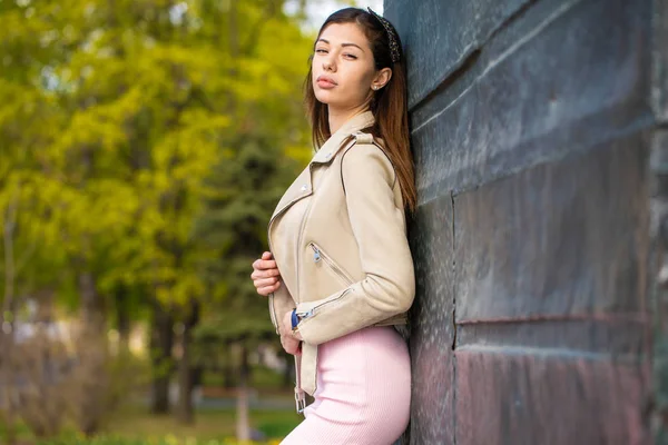 Beautiful young brunette woman in pink dress and gray jacket — Stock Photo, Image