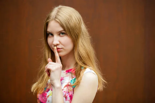 Junge schöne blonde Frau hat Zeigefinger auf Lippen als Zeichen gelegt — Stockfoto