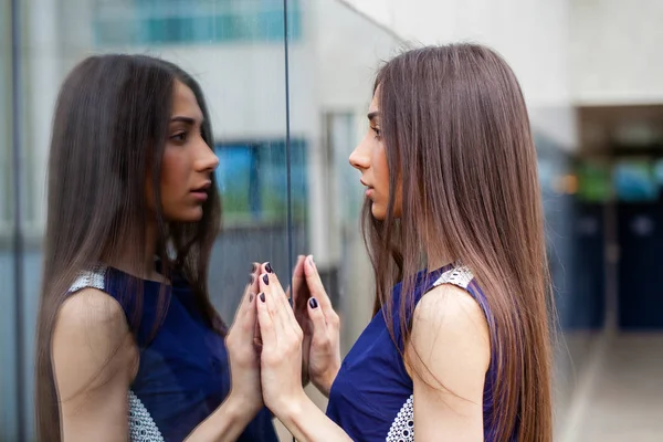 Elegante dama en vestido azul posando cerca de la pared espejada — Foto de Stock