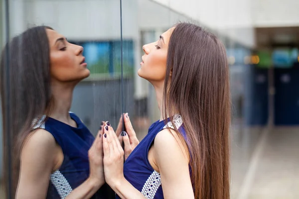 Elegante dama en vestido azul posando cerca de la pared espejada — Foto de Stock