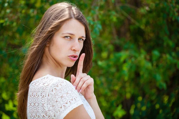 Young beautiful brunette woman has put forefinger to lips as sig — Stock Photo, Image