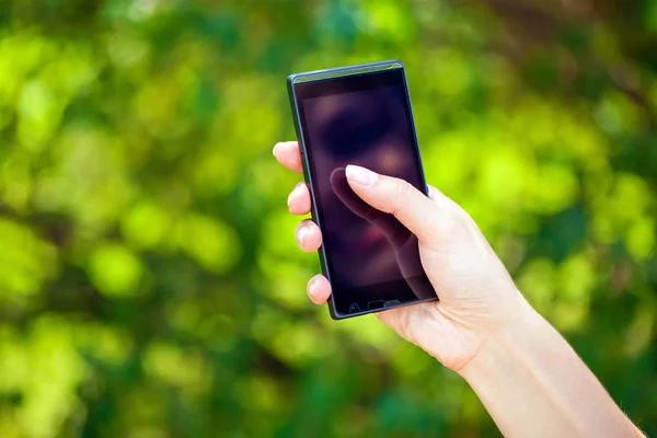Side view of a woman's hand holding a modern slick smartphone — Stock Photo, Image