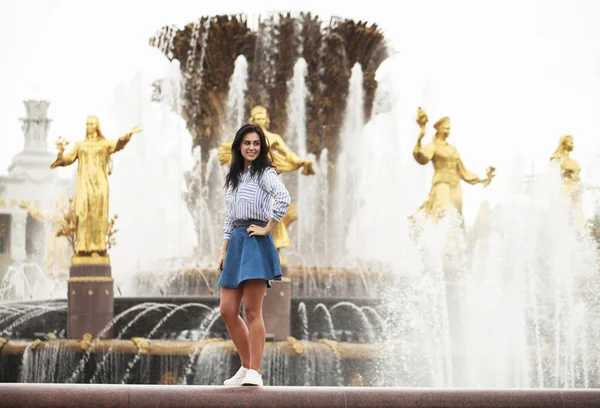 Jovem bela menina morena posando perto da fonte da cidade — Fotografia de Stock