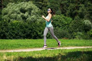 Atletik mutlu esmer kadın bir çayırda çalışma dışarı