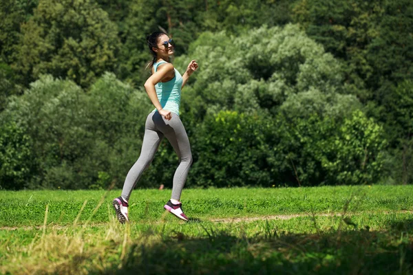 Atletik mutlu esmer kadın bir çayırda çalışma dışarı