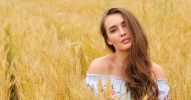 Bir buğday alan arka planda poz genç güzel kız 