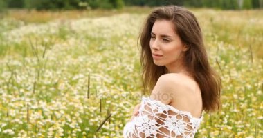 Genç güzel esmer kız bir papatya glade arka planı poz