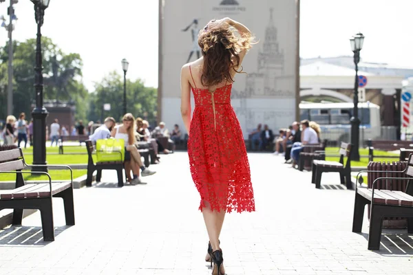Молода брюнетка в літній червоній сукні на фоні вулиці — стокове фото