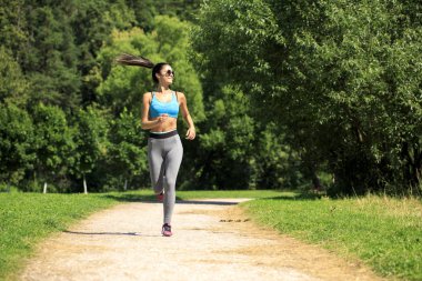 Atletik mutlu esmer kadın bir çayırda çalışma dışarı