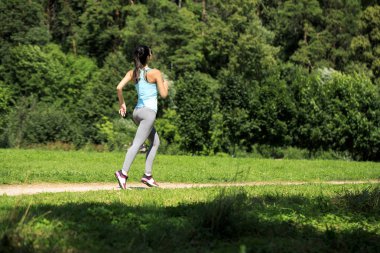 Atletik mutlu esmer kadın bir çayırda çalışma dışarı