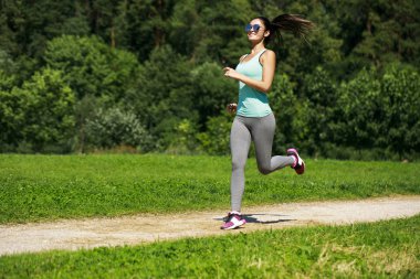 Atletik mutlu esmer kadın bir çayırda çalışma dışarı